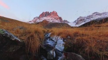 Juta Vadisi 'ndeki dağın zirvesinde dramatik kırmızı günbatımı sinematik zaman atlaması. Kazbegi Milli Parkı.