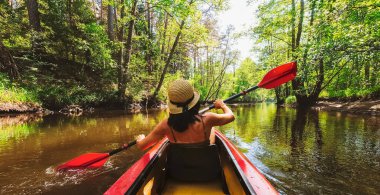 Nehirde kayak yapan çift. Güzel bir manzarada kano süren kadın ve erkek portresi. Sonbahar konsepti boyunca su sporları. Güz mevsiminde sakin, rahatlatıcı, ılık ağaçlar.