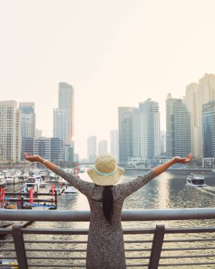 Dubai, BAE - 12 Ekim 2022: Heyecanlı turist kız el ele tutuşuyor ve Dubai Marina bölgesindeki muhteşem gökdelenlerin keyfini çıkarıyor. Birleşik Arap Emirliklerine Seyahat