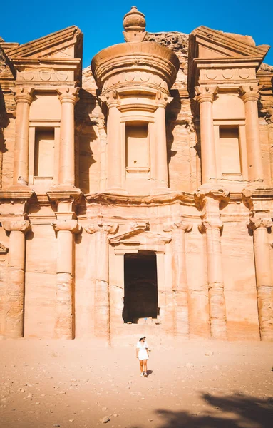 映画ペトラの背景白衣を着た白人の若い女性とペトラの最大の記念碑 ユネスコ世界遺産 ヨルダンのペトラA Deir修道院を楽しんで帽子 — ストック写真