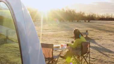 Turistler güneşli bir sabahta İzlanda 'nın resmi kamp alanında kamp minibüsüyle kamp yaparken kahvaltı yaparlar. Skaftafell kamp alanı ulusal parktaki buzulun yanında.