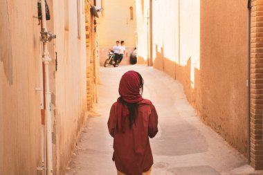 Beyaz kadın turist Yazd eski kasaba bölgesinde kemer koridorunda yürüyüş yapıyor.
