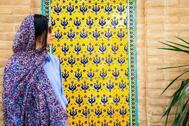 Kashan, Iran - 27th may, 2022: tourist stand pose for social media photo in public by wall with ornaments in traditional persian Fin garden Kashan, Iran