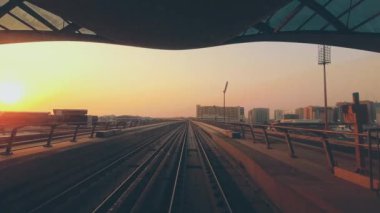 Dubai 'de Metro, Birleşik Arap Emirlikleri. FPV POV Fast Speed Motion 'da. Bulanık hareket halinde sürücüsüz metro. BAE 'deki fütüristik şehir silüeti turuncu gökyüzü günbatımında