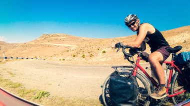 Beyaz erkek, yaz sıcağında tamamen çantalarla dolu sakin kırlarda bisiklet turu yapıyor. Yaratıcı ekolojik seyahat kavramı