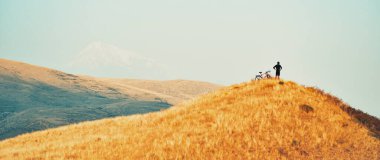 En tepedeki manzara, Ermeni Kafkasya 'da ilham verici dağ geçmişine sahip genç beyaz bisikletçiye uyuyor. Başarı, ilham, meydan okuma ve kararlılık kavramı