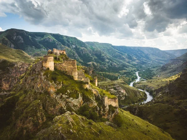 Aerial view historical Tmogvi fortress ruins with old wall on hilltop and church remains in scenic valley in summer