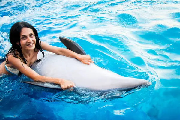 Caucasian woman swim with dolphin in pool. Batumi swim with dolphin experience concept
