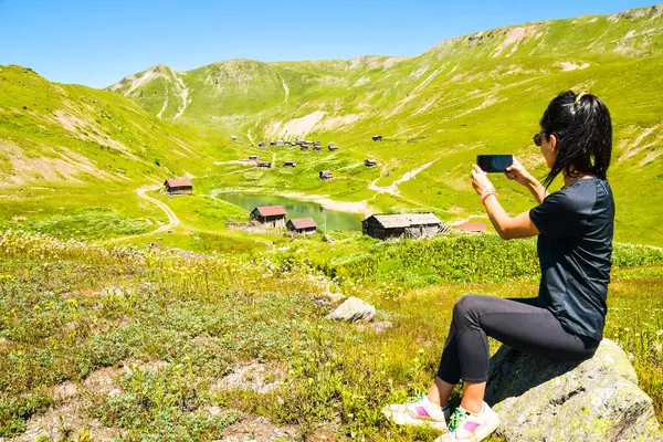Beautiful female traveler take photo of historical site on phone travel photo selfie outdoors in nature Travel alone on holidays and taking photo selfi