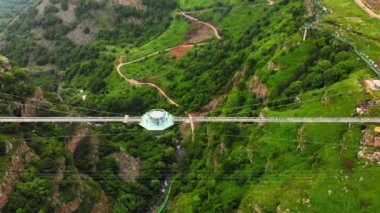 Dashbashi, Gürcistan - 19 Haziran 2022: Gürcistan kırsalındaki manzaralı dashbashi vadisinde cam köprü üzerindeki elmas şekilli platformun üzerinde uçmak. Kafkasya 'daki vadi üzerindeki ünlü modern köprü
