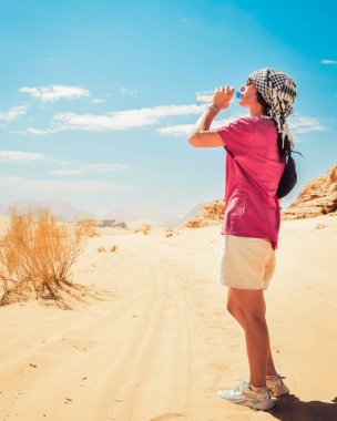 Caucasian woman thirsty drink cold fresh water in extreme heat in hot wadi rum desert outdoors on hiking trail clipart