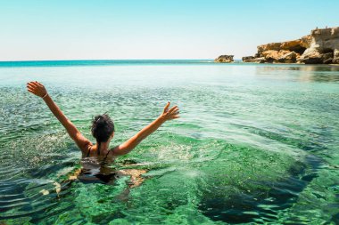 Kadınlar Kuzey Kıbrıs 'ta tatil yüzüşünün tadını çıkarırlar. Ayia napa körfezi kıyıları kristal berrak mavi Akdeniz suları ve deniz manzaralı kayalık kaya kıyılarıyla. Deniz mağaraları popüler seyahat merkezleri