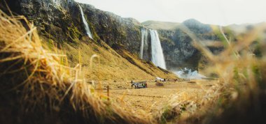 Seljalandsfoss, İzlanda - 5 Mart 2023: Turist grupları ilkbaharda İzlanda 'daki Seljalandsfoss şelalesini ziyaret ederler. Tatil sezonunun zirvesi bahar, yaz kalabalığı ve seyahat tatilleri