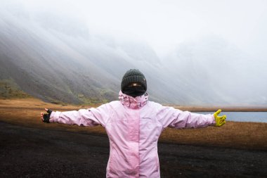 Close up caucasian woman wear gloves and warm clothes stand look at camera. Visit Iceland tourist attractions in harsh icelandic weather conditions clipart