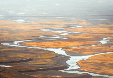 Top view of abstract blue glacier rivers pattern flowing through volcanic moss field in Icelandic highlands on summer