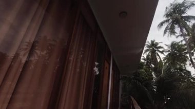 Zaman aşımı bütçesini kapat bulutlu bir günde balkon ve palmiye ağaçları manzaralı pansiyonda kal. Muson seyahati, sezon dışı bütçe dostluğu Maldivler 'de yerel konseptli konaklama