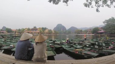 Turist çift ziyaretçileri geleneksel Vietnam şapkaları giyer ve kürek çekerek doğanın tadını çıkarırlar. Hoa Lu Tam Coc, Hoi An Antik Kasabası. Ünlü Vietnam seyahati