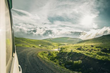 Arka planda 4WD arabanın önünden geçen POV dağlık arazide manzaralı yaz manzarası ile çevrili. Tusheti ulusal park turları ve Gürcistan turizm konsepti