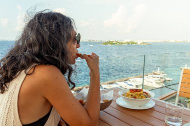 Erkek, Maldivler - 10 Mayıs 2024: Turistler lezzetli maldivler yer. İtalyan usulü makarna, çeşitli otlar, domatesler ve ızgara karideslerle birlikte. Maldivler mutfak konsepti