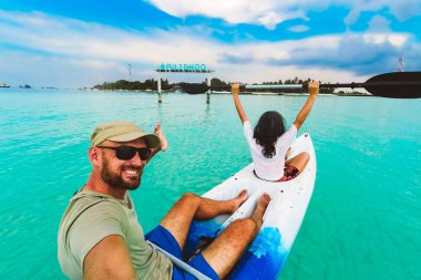 POV çifti, turkuaz tropikal sularda kayak yaparken selfie çekiyor. Maldivler 'de tatil. Fulidhoo adası kıyı şeridi ve spor faaliyetleri