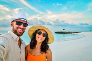 Maldivler 'de tatilde neşeli bir çift kumlu tropikal sahilde selfie çekiyor. Milenyum erkeği ve kızı yaz gününün tadını çıkarıyor. Birlikte kameraya gülümsüyoruz.