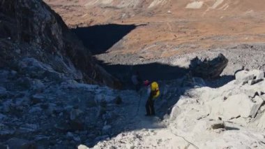 Himalayalar 'da, Gokyo Ri buzulundan geçen iki yürüyüşçü. Nepalli erkek rehber Sagarmatha Ulusal Parkı resmi yürüyüşünde turist müşterisine öncülük ediyor.