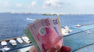 Erkek, Maldivler - 7 Mayıs 2024: Limandaki restoranda çeşitli maldivian paraları turistlerin elinde. Tatil giderleri ve Maldivler iş ekonomisi kavramı