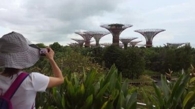 Singapur, Singapur - 15 Mart 2024: Turist ünlü cazibesinin akıllı telefon fotoğrafını çekti. Marina Sands manzaralı günbatımında süperağaç ormanına bakıyor. Singapur seyahat hedefi kavramı