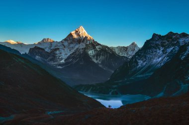 Ama dablam dağ zirvesi ve Cholatse gölü. Sagarmatha Ulusal Parkı. Ama Dablam - Nepal 'in Koshi eyaletinin doğu Himalaya bölgesinde bir dağ. Ana tepe. Erkek ve kadın yürüyüşçü.