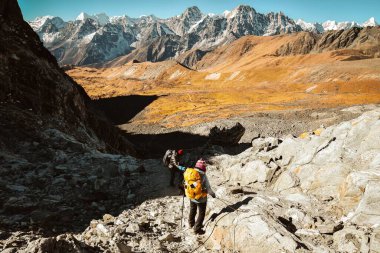 Himalayalar 'da Chola' dan geçen iki yürüyüşçü Gokyo Ri 'ye halat kullanıyor. Nepalli erkek rehber Sagarmatha Ulusal Parkı resmi yürüyüşünde turist müşterisine öncülük ediyor