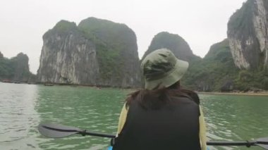 Ha Long Körfezi, Vietnam - 8 Mart 2024: Kafkas kadın turist kayığı ile Ha Long körfezinde karga tekneleriyle tatil yapıyor.