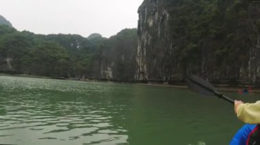 Ha Long Bay, Vietnam - 8 Mart 2024: Kireçtaşı dağlarıyla sakin tropikal körfezi keşfeden kadın. Ha Long Körfezi, Vietnam