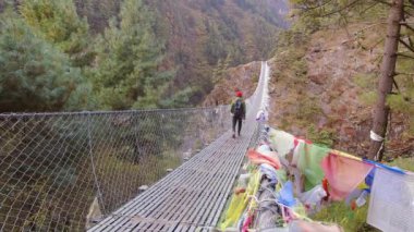 Beyaz erkek trekker Everest ana kampına tek başına giderken ünlü Hillary asma köprüsünden geçiyor. EBC yürüyüşü. Nepal 'de popüler Himalayalar' ın açık havada zorlu yürüyüşü