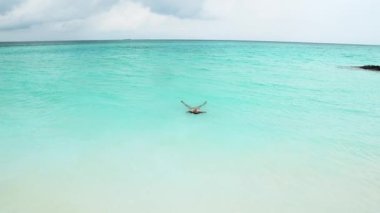 Su yüzeyinde kristal berraklığında turkuaz bir okyanusta yüzen sarı mayolu genç ve seksi bir kız. Mutlu ada yaşam tarzı. Cennet 'te Tatil.