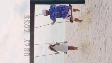 Genç, kaygısız, beyaz, gerçek bir çift aşık gülümsüyor ve Fulidhoo Adası 'nda balayı manzaralı salıncaklarda salıncakta sallanıyor. Maldivler tatil konsepti