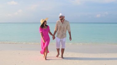 Güzel gezgin çift güneş doğarken tropikal sahilde yürürler. Fulidhoo adasında güneşin doğuşunu izlerler. Romantik tatil