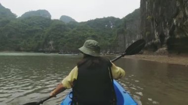 Ha Long Körfezi, Vietnam - 8 Mart 2024: Kafkas kadın turist kayığı ile Ha Long körfezinde karga tekneleriyle tatil yapıyor.