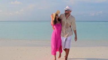 Güzel gezgin çift güneş doğarken tropikal sahilde yürürler. Fulidhoo adasında tatilin tadını çıkarırlar. Romantik tatil tatili. Gerçek duygular otantik gerçek insan ilişkileri