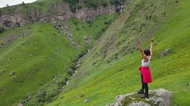 Hava manzaralı mutlu kadın yürüyüşçü dağın tepesinde, dağlara karşı duruyor. Georgia, Kafkasya Dağları 'nı gezerek geziyor.
