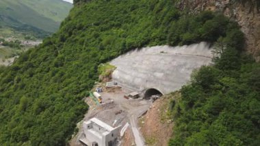 Kazbegi, Gürcistan - 7 Temmuz 2024: Çinli inşaatçılar tarafından inşa edilen yeni otoyol projesinin inşaat sahasında havadan görüş vinçleri ve köprü temel direkleri. Çığ baypas tüneli. Tbillisi - Lars