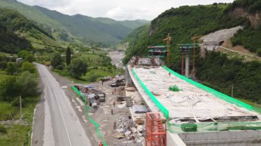 Kazbegi, Gürcistan - 7 Temmuz 2024: Çinli inşaatçılar tarafından inşa edilen yeni otoyol projesinin inşaat sahasında havadan görüş vinçleri ve köprü temel direkleri. Çığ baypas tüneli. Tbillisi - Lars