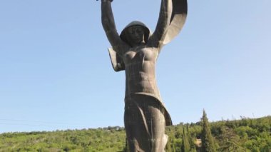Tiflis, Gürcistan - 4 Temmuz 2024: Popüler dev Sovyet mimari heykeli. Zafer anıtı. Kollarını kaldıran ve elinde meşe yaprakları olan bir kadın.