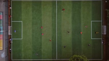 Havadan aşağıya bakan iki erkek takım yeşil suni futbol sahasında futbol oynuyor. Sağlıklı spor ve çocukların yaz aktiviteleri