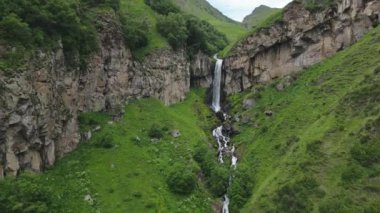 Yeşil Kafkasya dağlarında Arsha şelalesi manzaralı hava zoom 'u. KAzbegi Ulusal Parkı. Görecek ve yapacak şeyler. Popüler gezi gezisi eğlencesi. Gürcistan seyahat hedefi kavramı