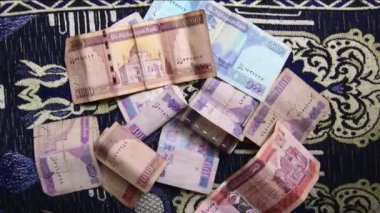 Yavaş çekimde yakınlaştır. Otel odasındaki ahşap masa üzerinde yüz bin Afgan banknotu. Afganistan ekonomisi ve turizm sektörü kâr kavramı