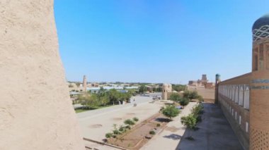 Khiva, Özbeksitan - 11 Ekim 2023: Khiva Müzesi şehir duvarları ve güneşli yaz gününde tarihi restore edilmiş binalar. Duvarlarda yürüyen POV Özbekistan tarihi mirasını geziyor
