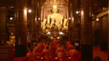 Buda heykelinin yanındaki tapınaktaki dua eden rahiplerin bulanık arkaplanlarını kopyala