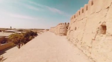 POV turisti 10 metre yüksekliğinde Khiva eski şehir duvarları boyunca yürüyor. Duvar inşaatı için kil. Khiva şehri gezisi cazibesi