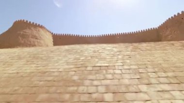 POV turisti 10 metre yüksekliğinde Khiva eski şehir duvarları boyunca yürüyor. Duvar inşaatı için kil. Khiva şehri gezisi cazibesi