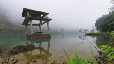 Zaman aşımına uğramış doğa manzarası. Nehir suyu seviyesi hızla düşüyor. Manzaralı, bereketli Asya tropikal manzarası ve sisle çevrili beton bina yapısı ile çevrili.